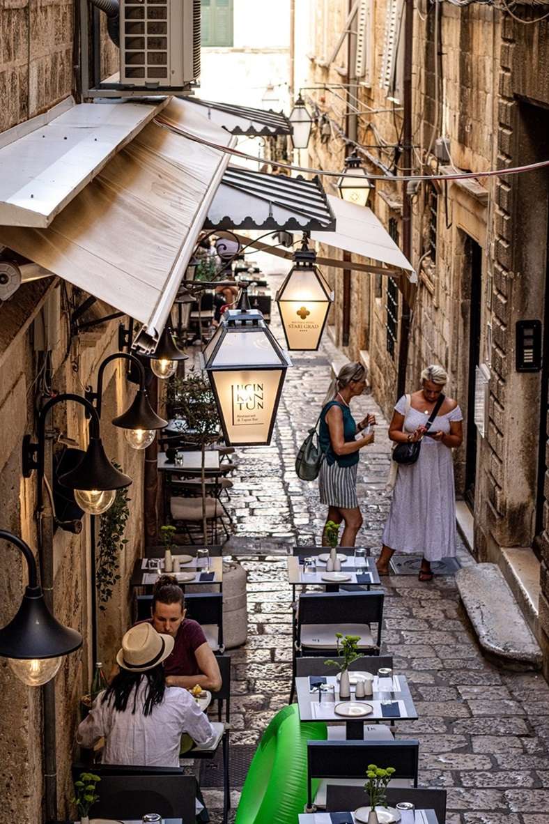 Restaurant and people standing in a narrow alley